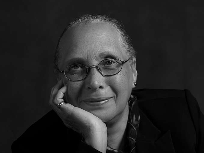 Connie smiling at the camera. She is wearing glasses in front of a photo backdrop.