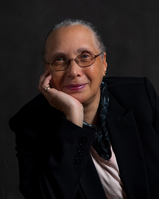 Connie Harold smiling while looking at the camera with her head resting on her right palm.