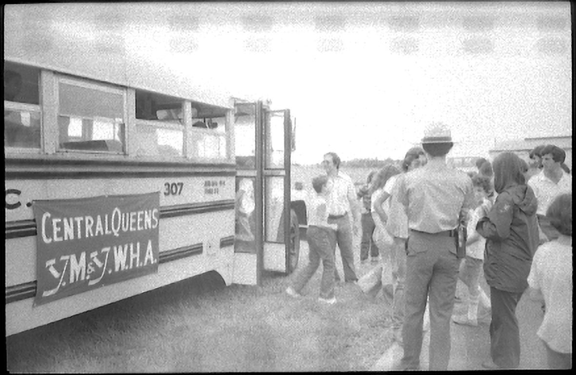 Students exiting a bus. The bus has a banner that reads, "Central Queens Y.M. & Y.W.H.A."