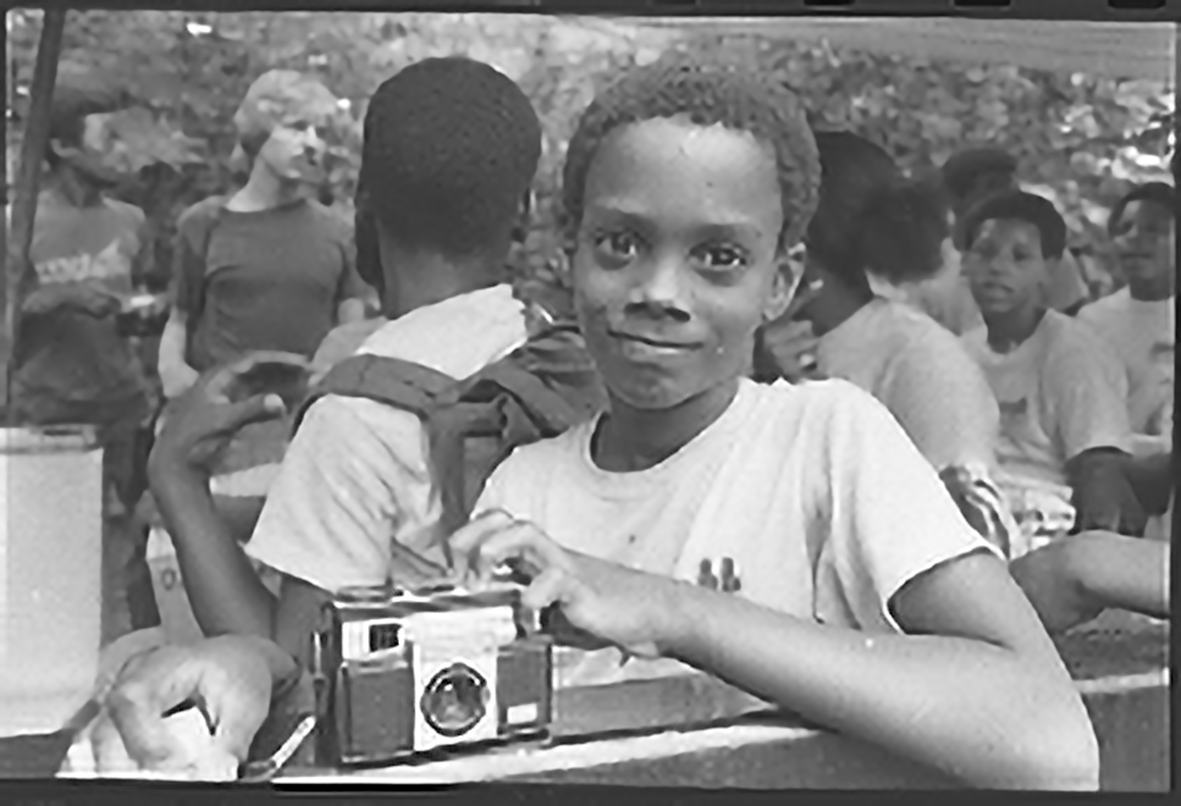 Child smiling and holding a camera