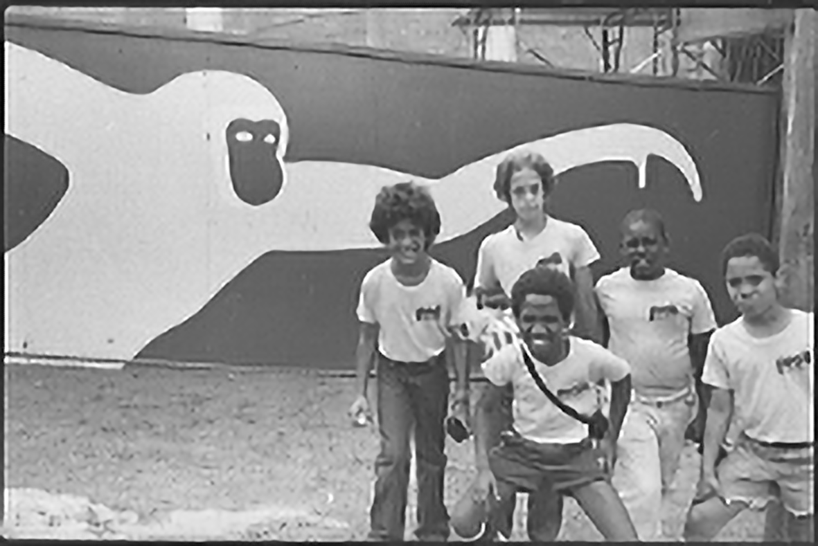 A group of students smiling in front of a mural of a monkey