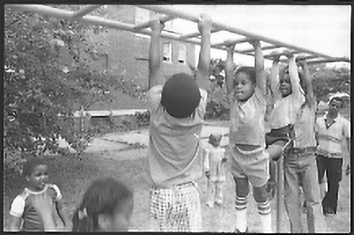 A group of children hanging on the monkey bars at a playground