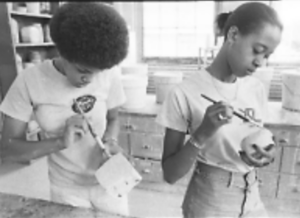 two students painting coffee mugs