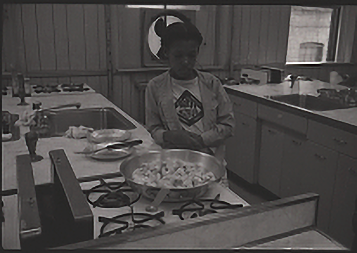 A student looking down at a frying pan with diced food cooking.