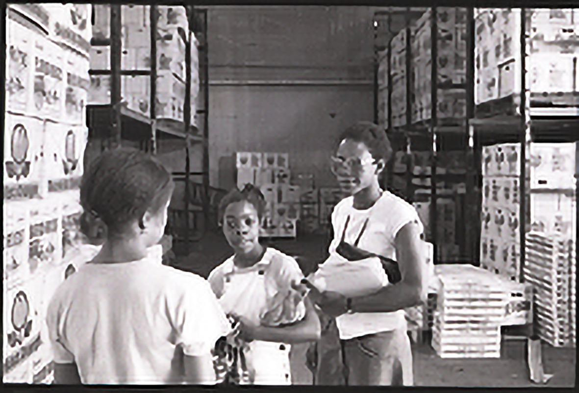 two students next to a counselor at Hunt's Point Market. They are surrounded by shelves of merchandise.