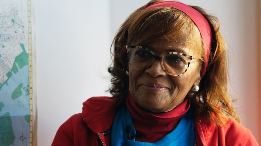 Joan O'Bryan being interviewed. She is wearing a red sweatshirt and glasses.